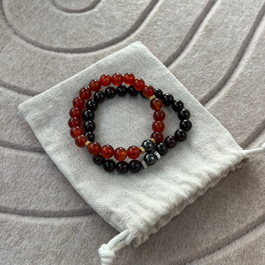 Duo de bracelets La Braise en cornaline et grenat posé sur son pochon en coton