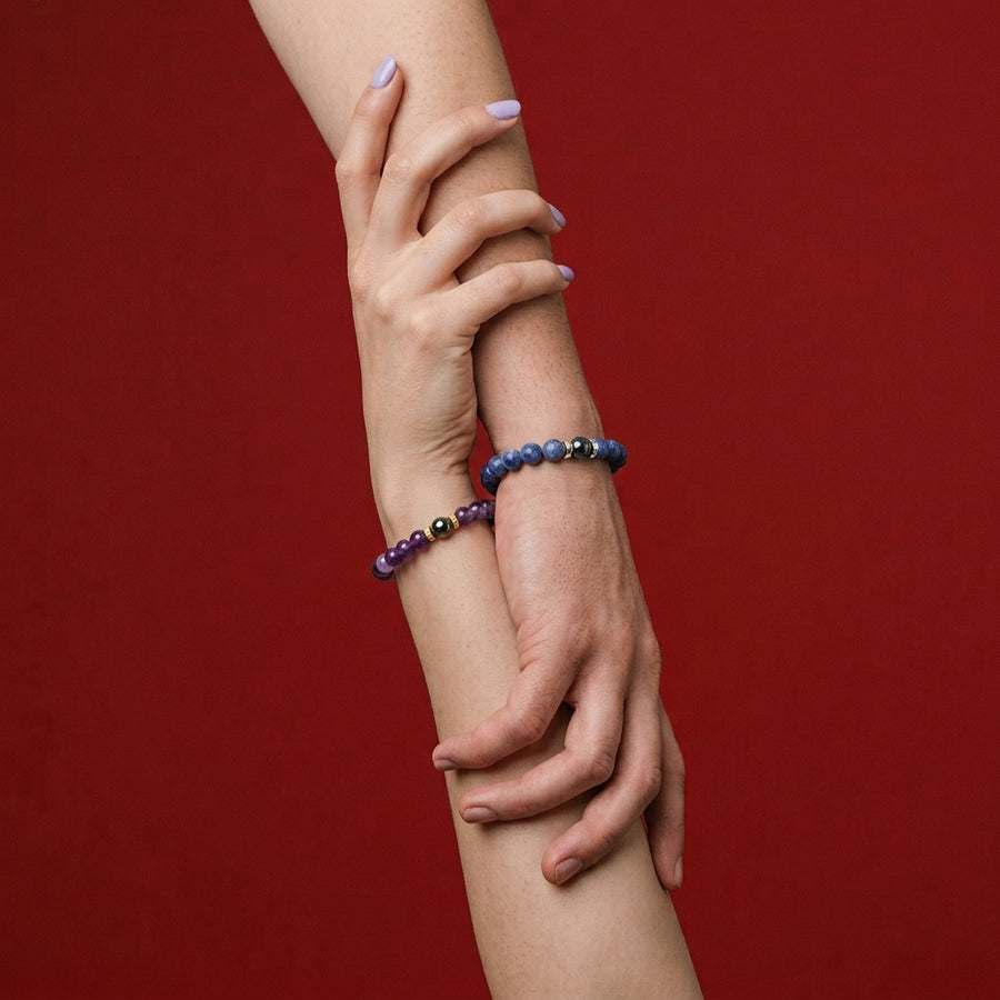 Deux poignets enlacés portant les bracelets de couple en améthyste et sodalite